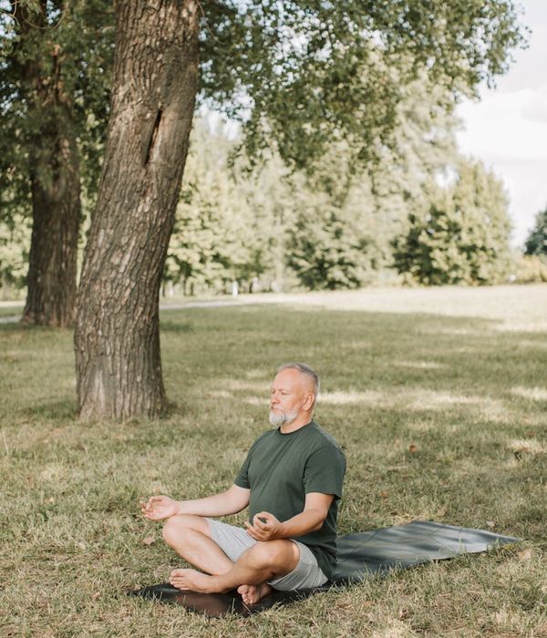 Person sitting cross-legged meditating peacefully in a minimal setting.